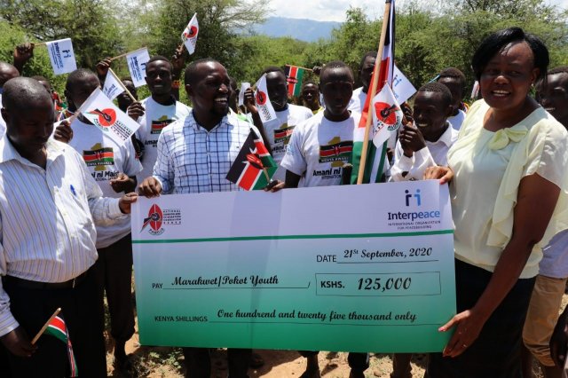 Commissioner Hon. Dorcas Kedogo (right)handing over a cheque to the Pokot and Marakwet youth who had jointly cleared the road that join Chesongoch and Tilingwa on 21st September, 2020 to ease movement between the two communities.